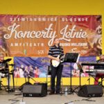 Na zdjęciu muzycy zespołu Eminence - Wokalista i gitarzysta, klawiszowiec oraz perkusista. Za nimi na żółtej ścianie wiszą dwa banery reklamujące imprezy. Foto Monika Bilska