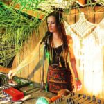 Kobieta stojąca przed mikrofonem, przed nią stół ze sprzętem DJ.